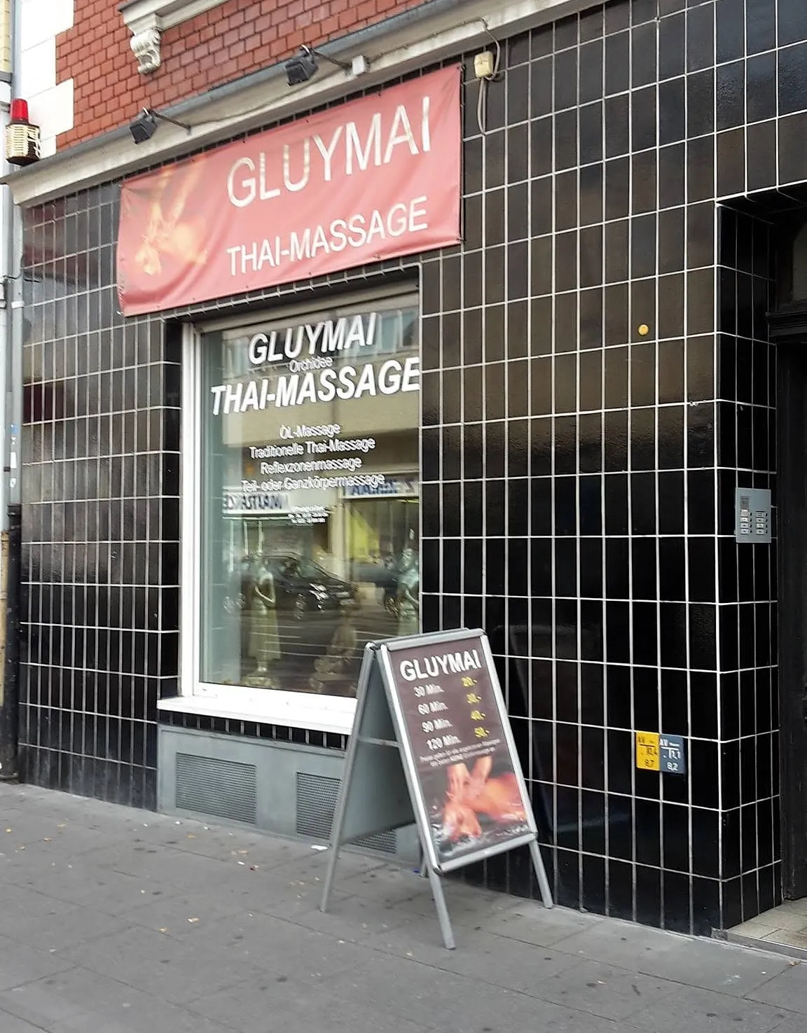 Ladenfront des Studios mit rotem GLUYMAI-Banner an der Bonner Straße