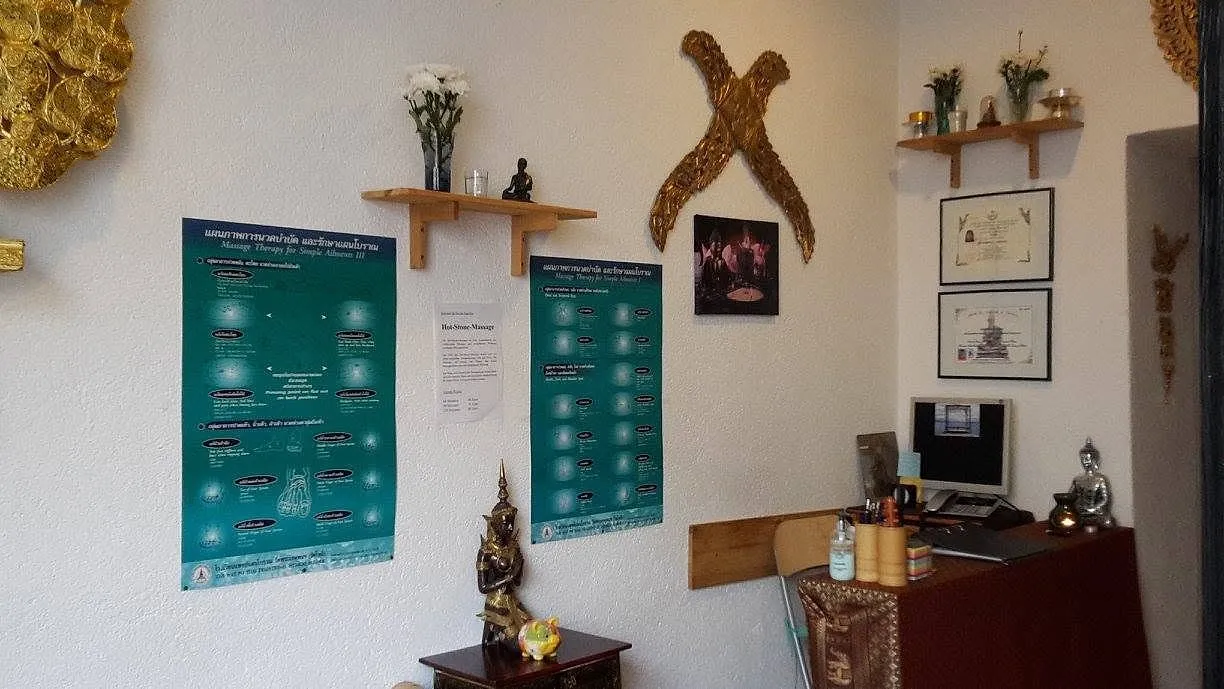 Empfangsbereich mit Buddhafigur, Blumen und Massageölen