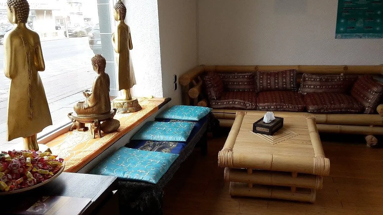 Wartebereich mit Bambusbank, blauen Sitzkissen und goldenen Buddhafiguren